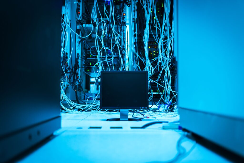 Computer plugged into servers in a blue room by Panumas Nikhomkhai on Pexels: https://www.pexels.com/photo/monitor-and-wires-behind-17489155/