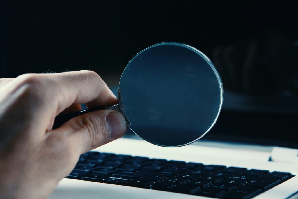 Person looking through a magnifying glass at a computer screen by Sasun Bughdaryan on Unsplash: https://unsplash.com/photos/person-holding-round-blue-frame-5T0MpCaw7gM
